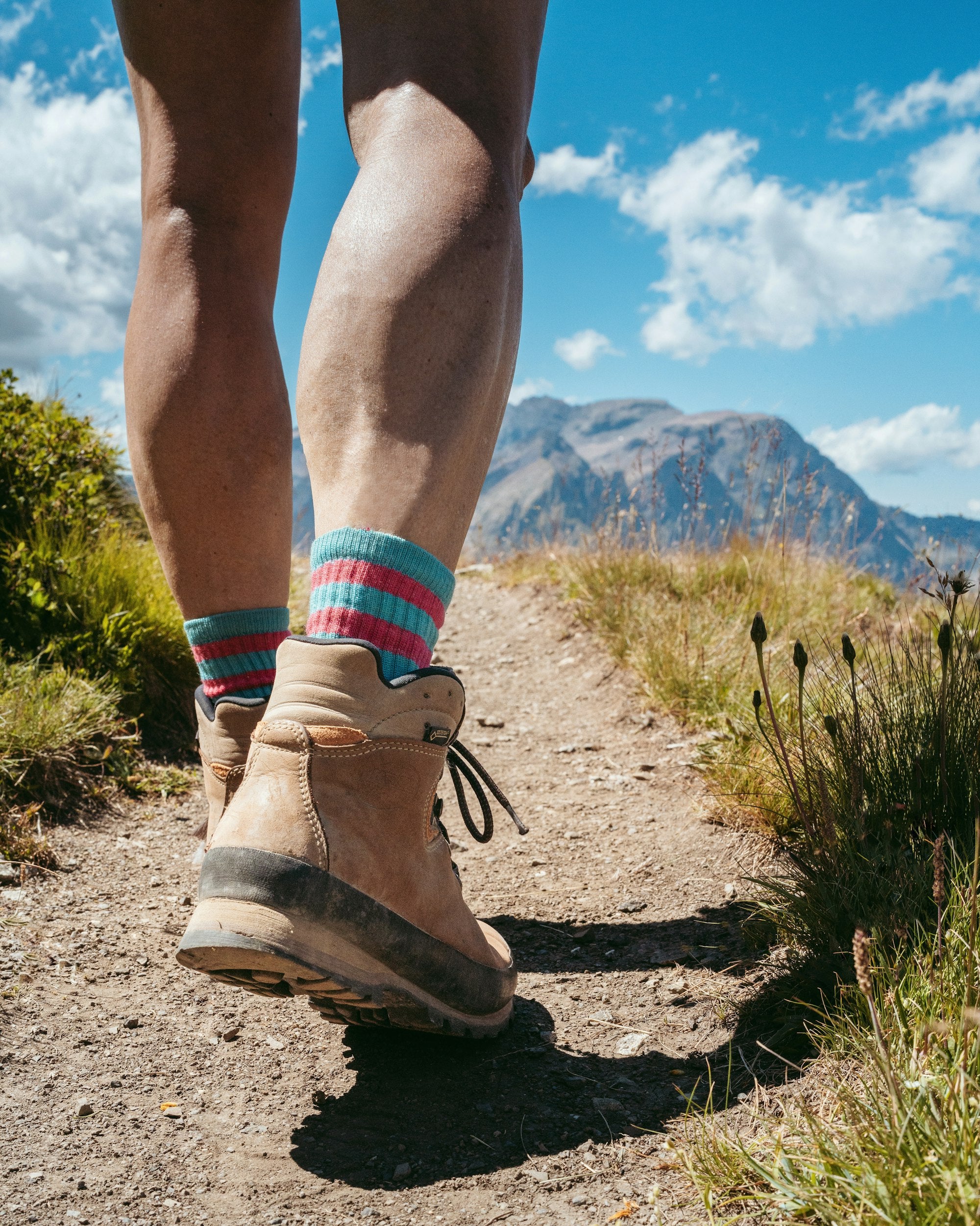 Woman hiking on dirt trail with mountain landscape background